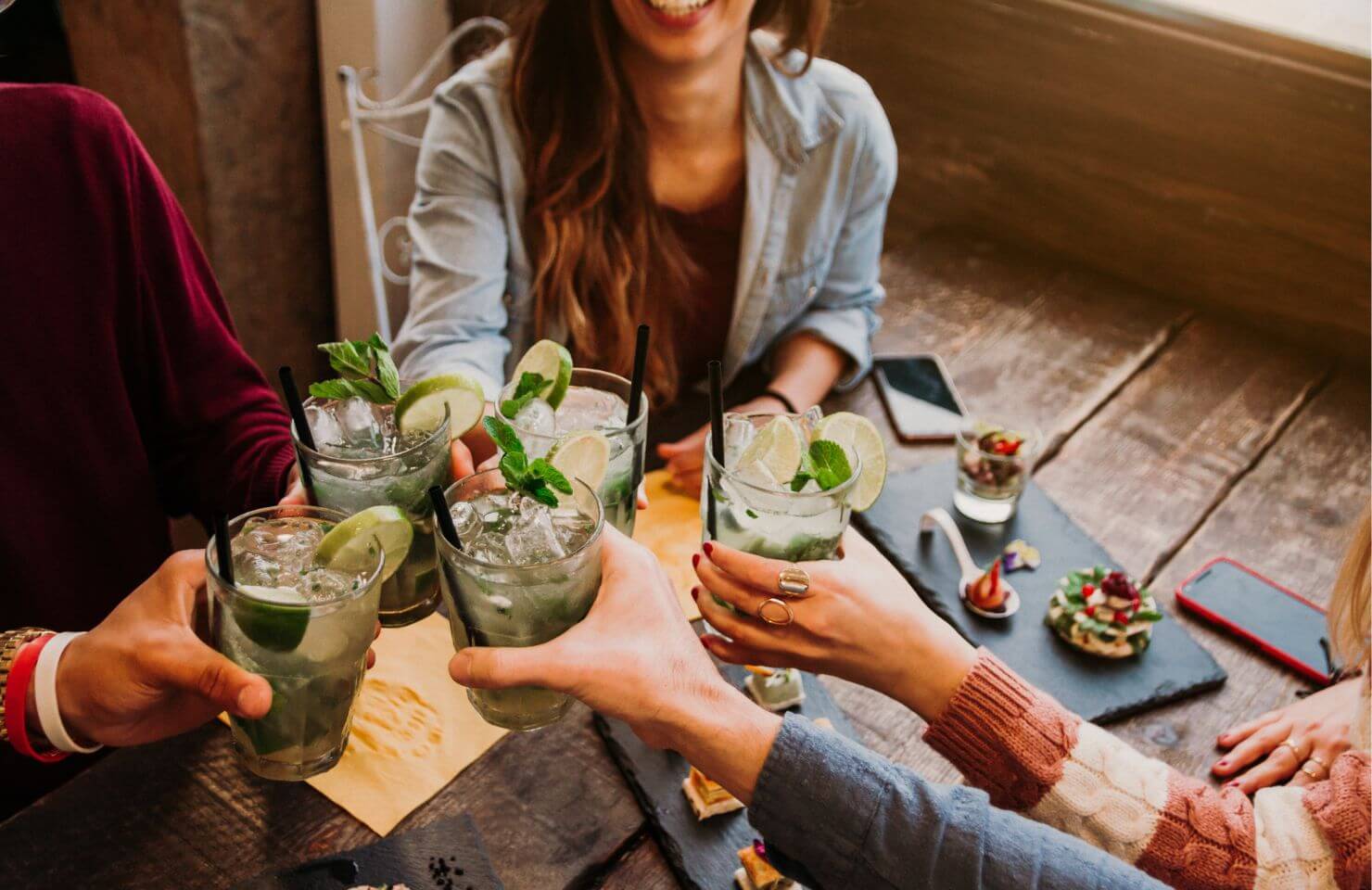 Group of friends cheering with Mojito in a Bar