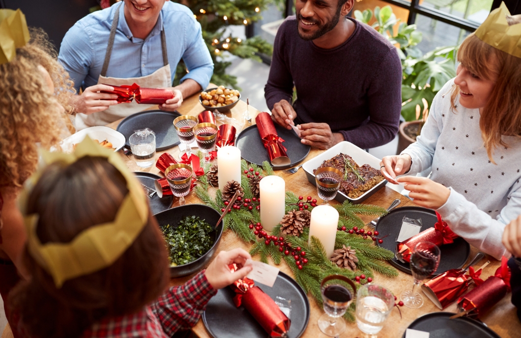 Freunde am Tisch mit Christmas Crackern und Papierkronen