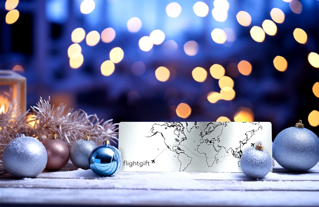 Flightgift Geschenkkarte liegt im Schnee neben Weihnachtskugeln