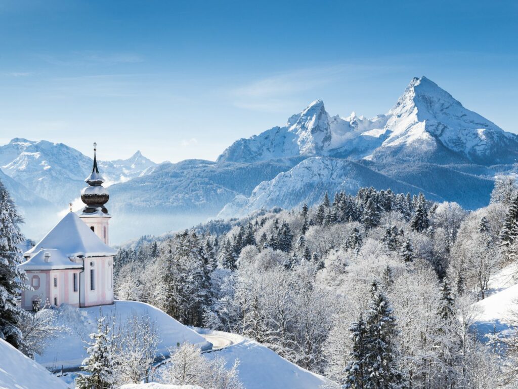 a church on a hill with snowy mountains during Christmas in Germany