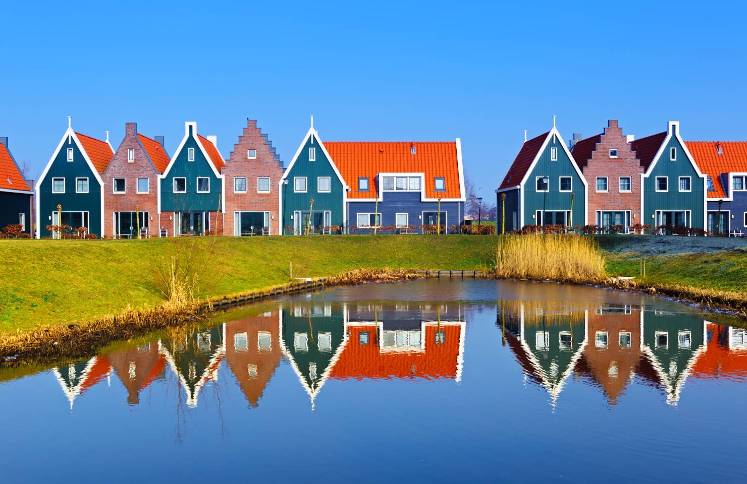 bunte holländische Häuser blicken im Sonnenschein auf einen Fluss