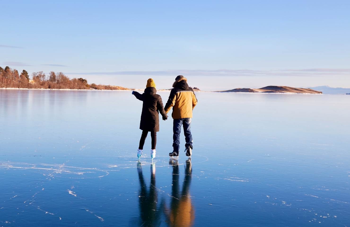 two people ice skating on a frozen lake in the winter