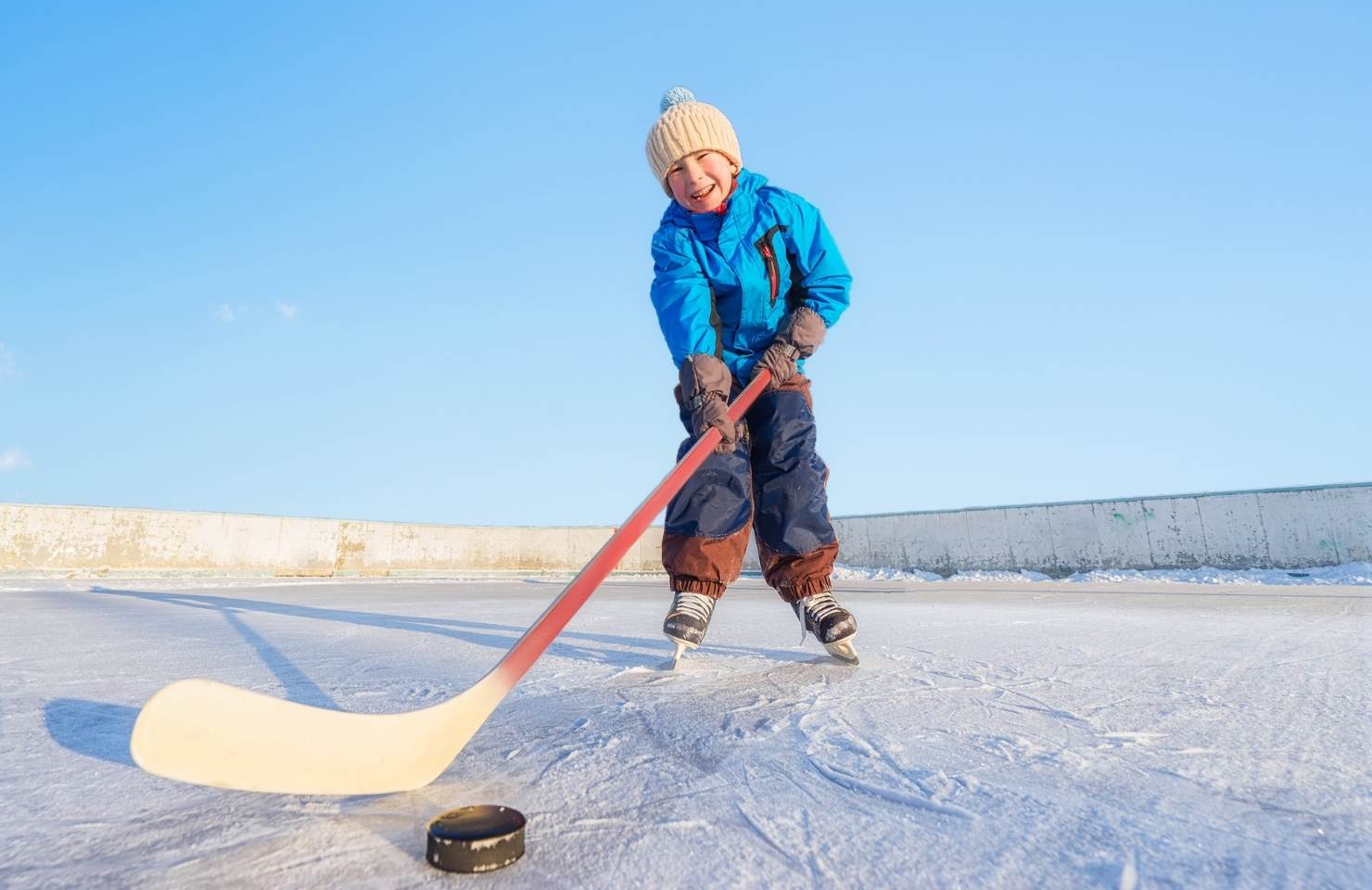 a child playing ice hockey on a frozen pond in the winter