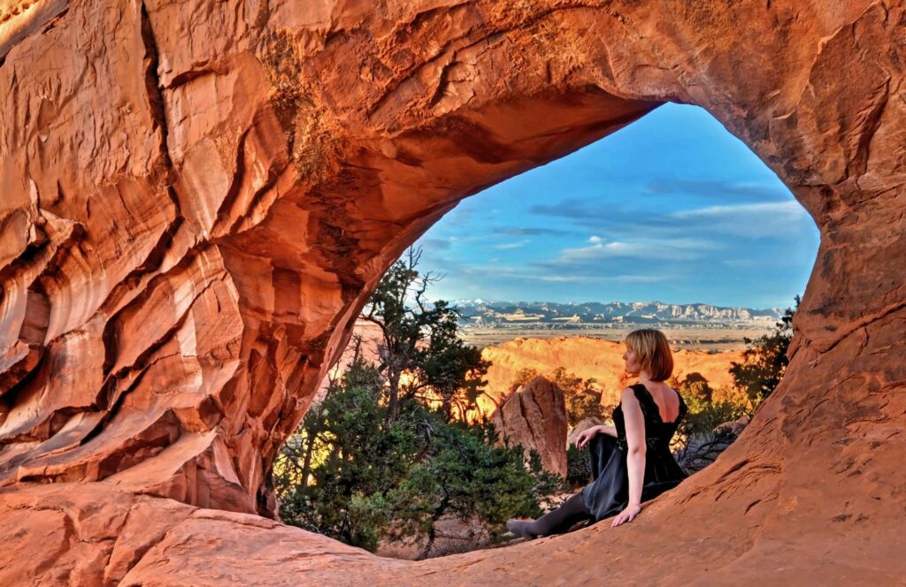 vrouw zittend op een van de bogen van moab utah