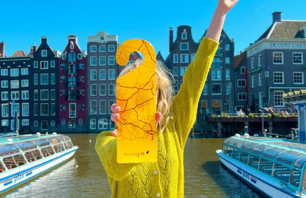 Cheque regalo de hotel en manos de una mujer con jersey amarillo