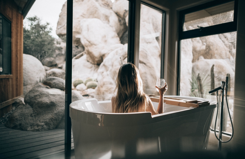 Vrouw zittend in een badkuip in een spahotel met een glas wijn in haar hand