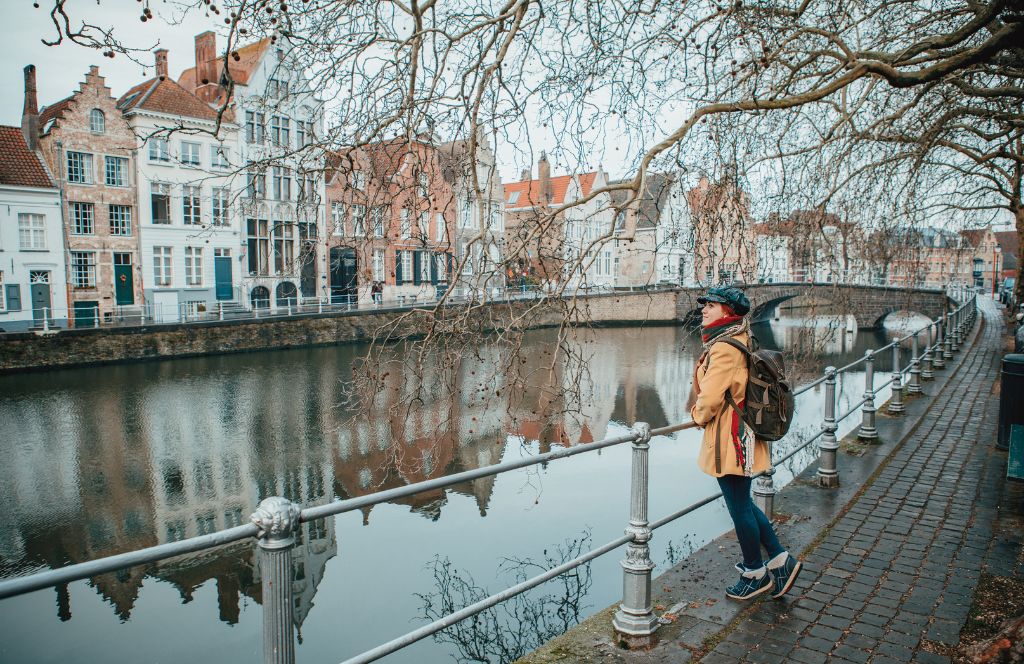 eine Frau überblickt einen Kanal in Brügge im Winter