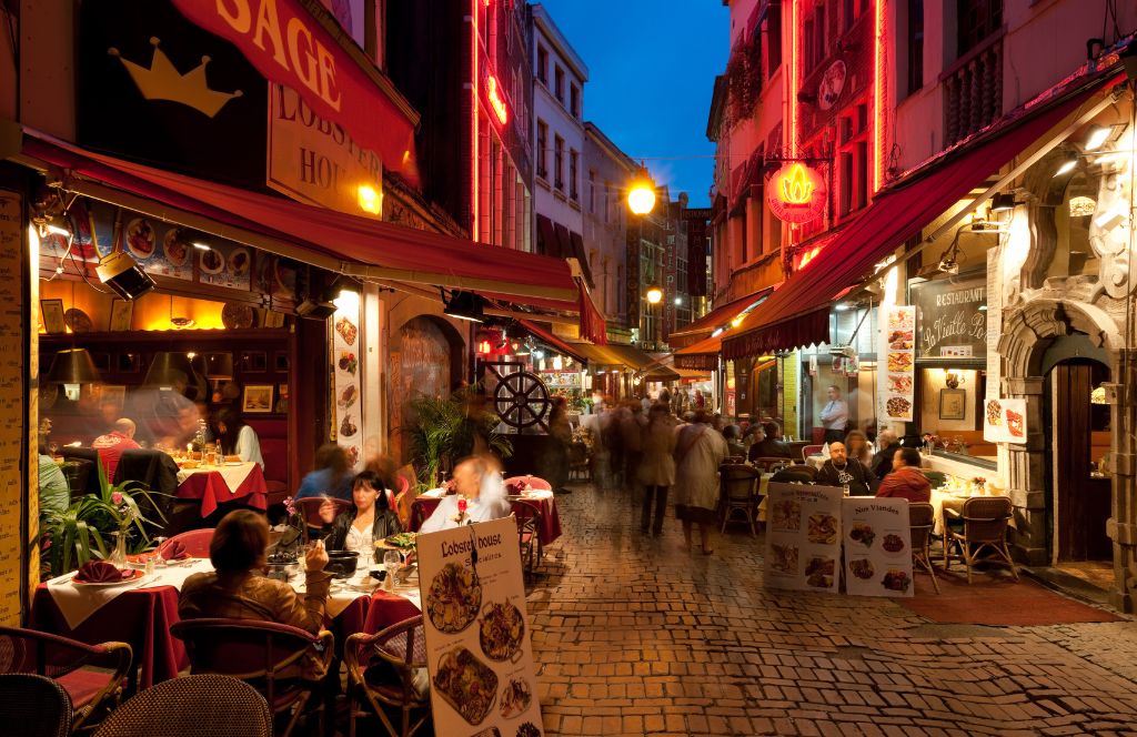 una calle de bruselas de noche con restaurantes y bares