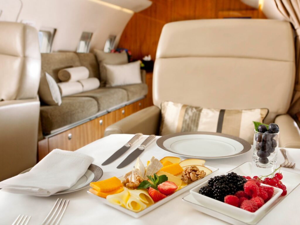 ein Teller mit frischem Obst, Käse und Nüssen auf einem Erste-Klasse-Flug