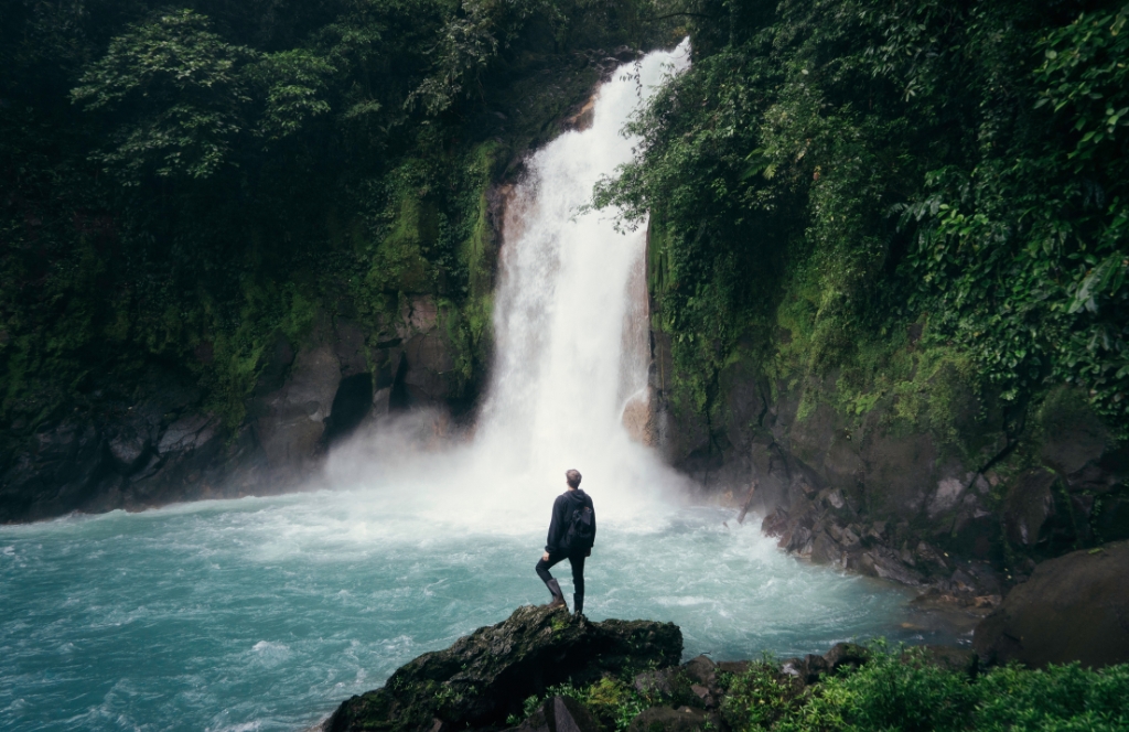 Mann steht vor einem Wasserfall
