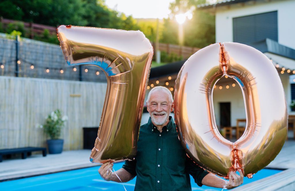a man holds balloons on his 70th birthday
