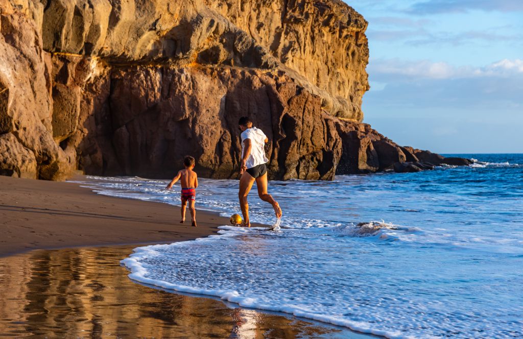 vader en zoon voetballen op strand tijdens familie vakantie spanje 