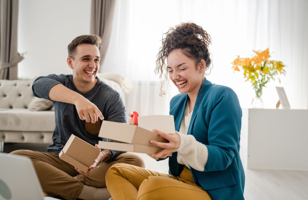 a couple open the wedding gifts given to them via their wedding gift list