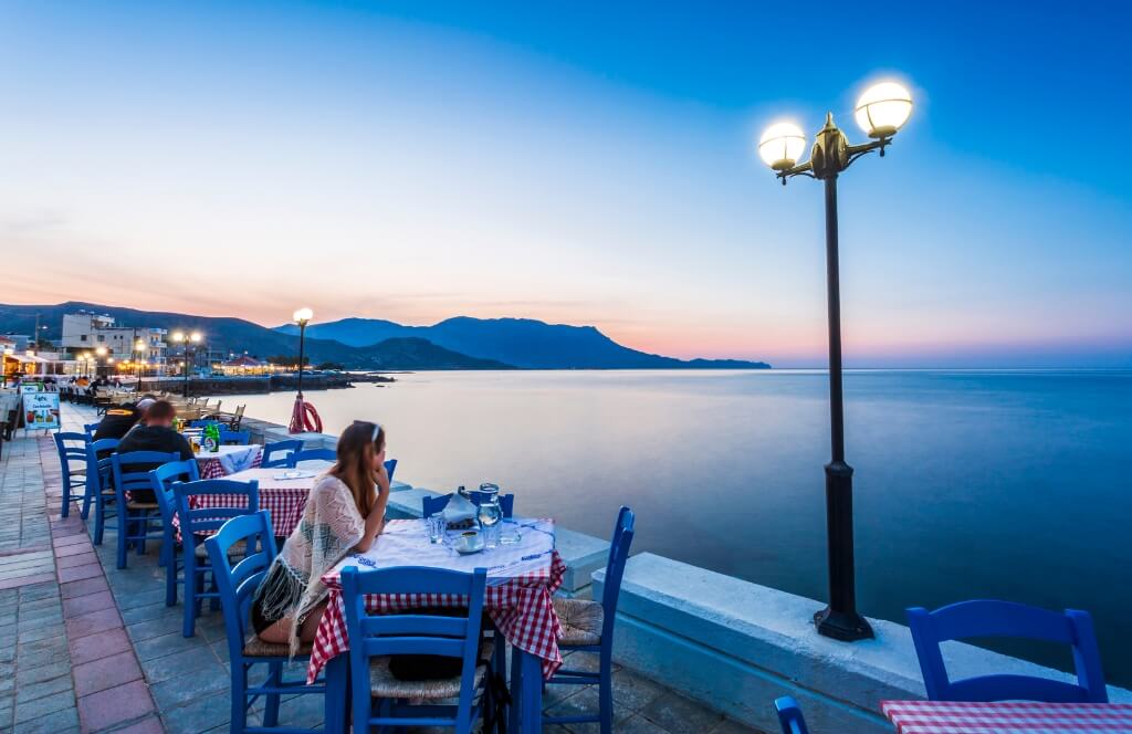 Une voyageuse attablée dans un restaurant en Crête où partir en mai en Europe