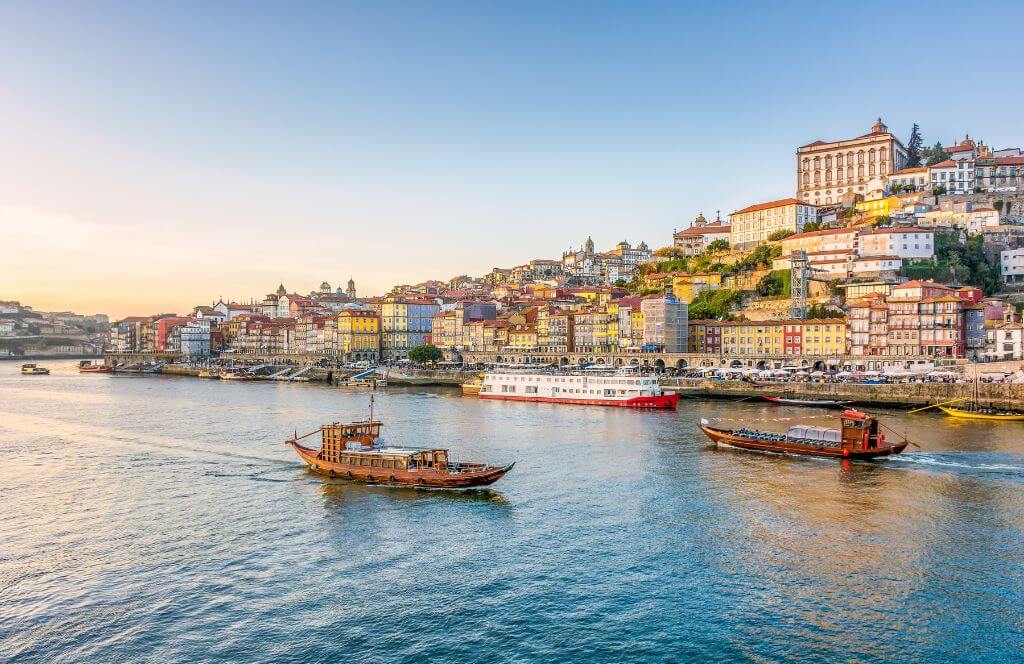 Scenic view of the city of Porto in Portugal in warm winter sunset light with boats and Douro river in the foreground