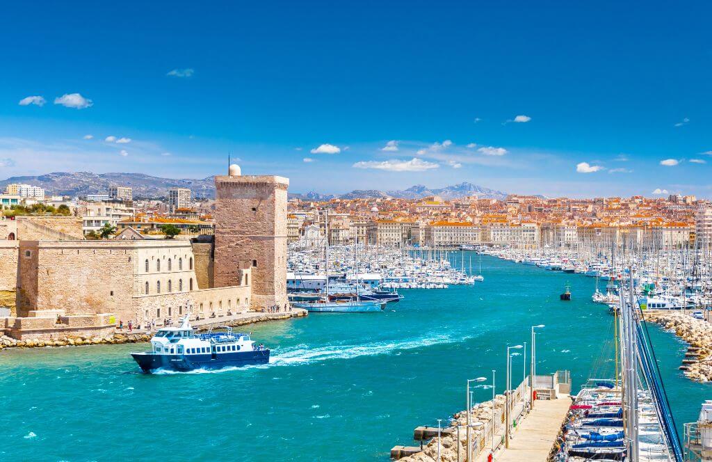 Aerial panoramic view of Marseille Old Port with yachts, boats, and the city mountains in the background. Marseille, Provence, France. Holidays in France