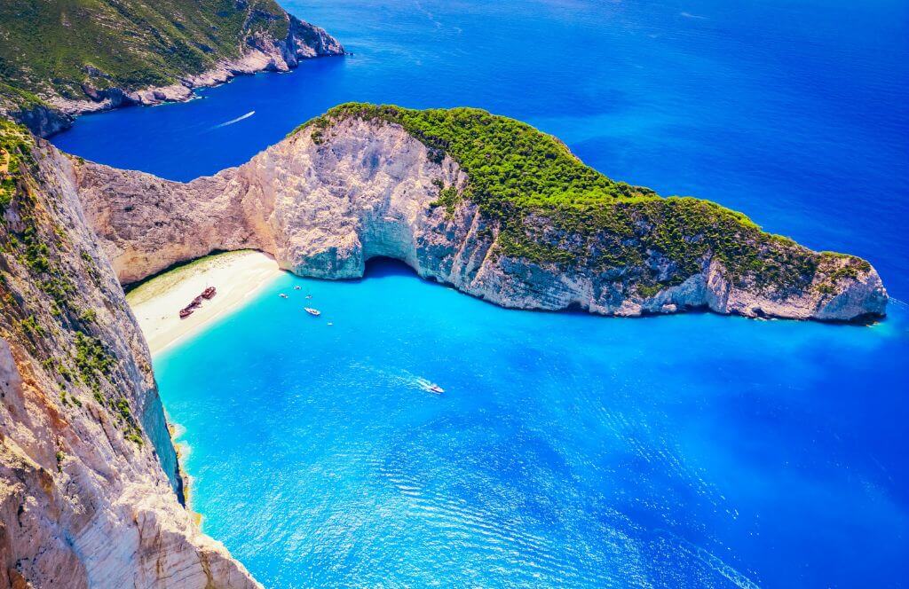 Ferry boats in the turquoise lagoon surrounding the iconic Shipwreck Beach (Navagio Beach), aerial view, Zakynthos, Greek Islands, Greece, Europe