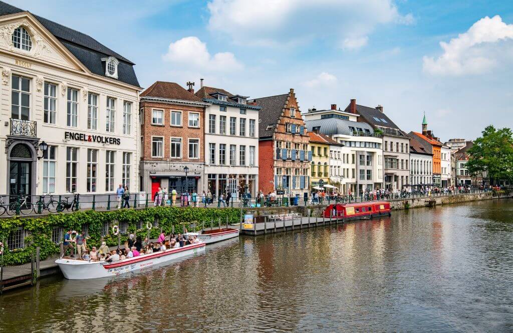 Pretty townhouses perched on the bank of the River Leie in the historic centre. Historic buildings by the side of a picturesque quay.