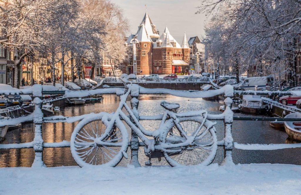 Canales de Ámsterdam en invierno con bicicletas cubiertas de nieve y casas típicas