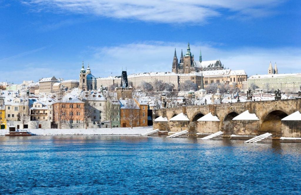 Praga cubierta de nieve con el Puente de Carlos y la Ciudad Vieja al fondo