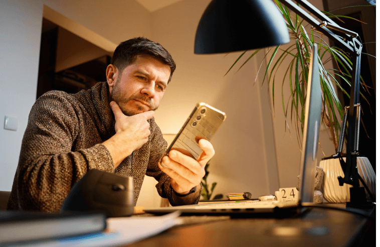 Man looking at a phone wondering if there is an ideal time to book flights